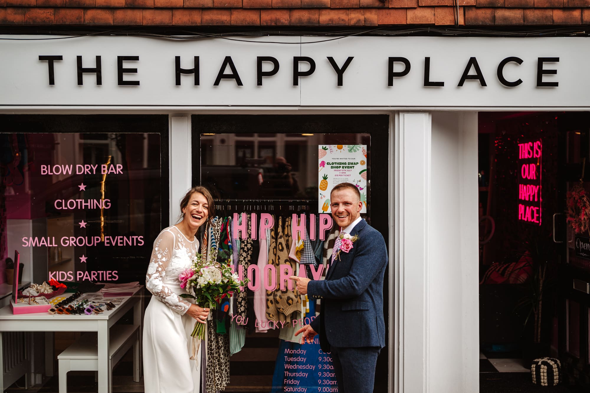 A couple smiling in front of a shop called The Happy Place. One of my favourites from me Best of 2024 Documentary wedding Photography