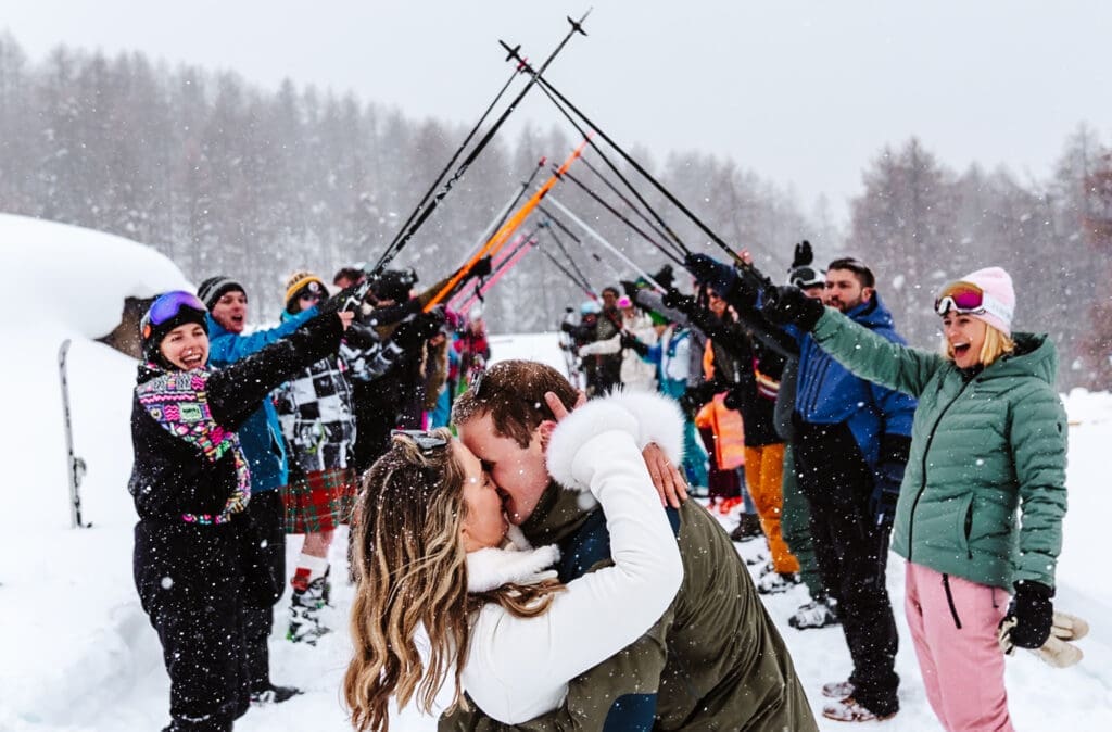 A wedding on a mountain, the couple kiss in front of an arch of ski poles, some of my Best of 2024 Documentary wedding Photography