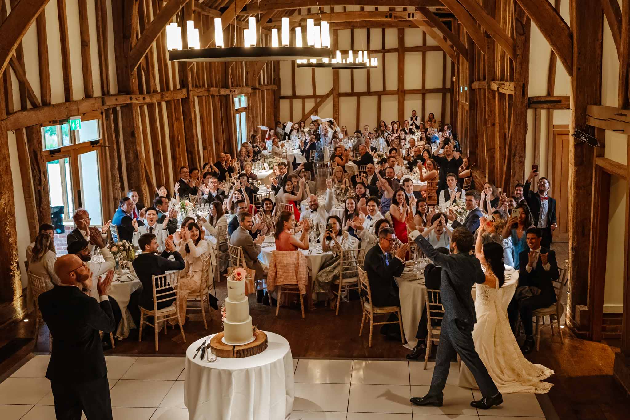 Bride and groom enter the great barn for their wedding breakfast,  captured in Micklefield Hall wedding photography, by Ben Lee