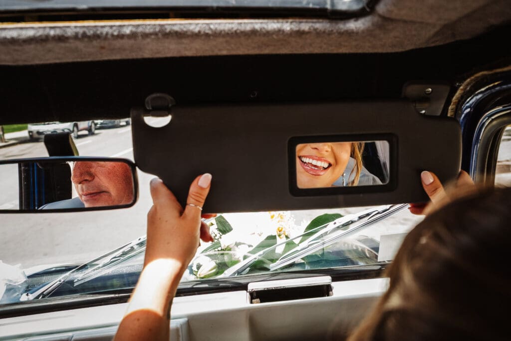 reflection of bride's smile in mirror of wedding car captured in wedding photography in Tangier, Morocco by Ben Lee.