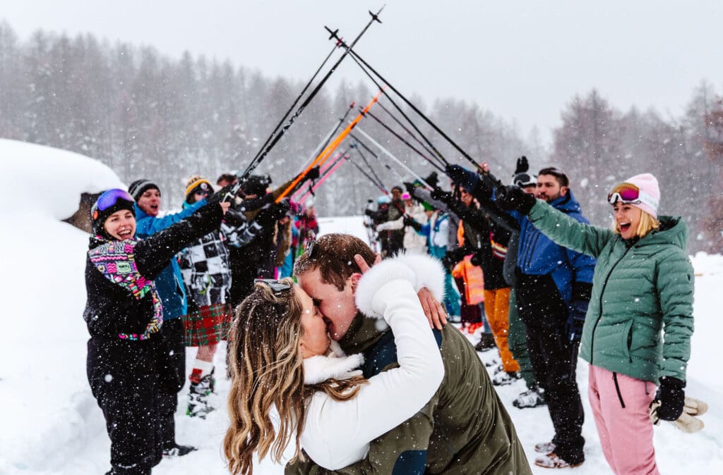 bride and groom kissing in front of ski pole walkway captured captured in ski wedding photography in Italy, by Ben Lee