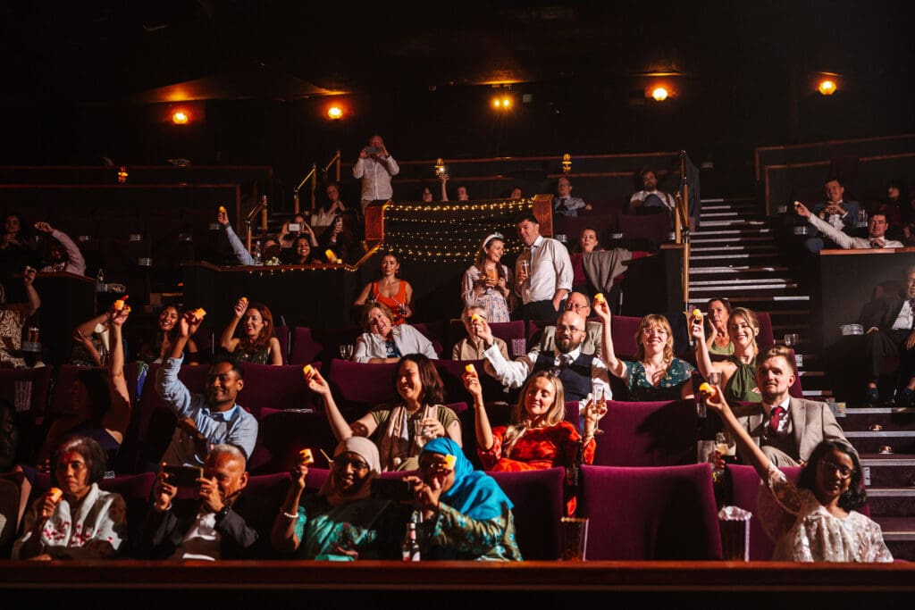 Guests cheering from their seats at a unique and fun cinema wedding in Manchester, captured by Ben Lee Photography